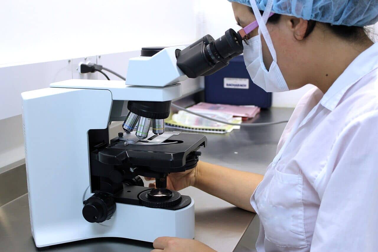 Technician looks into a microscope as part of the cervical cancer screening process