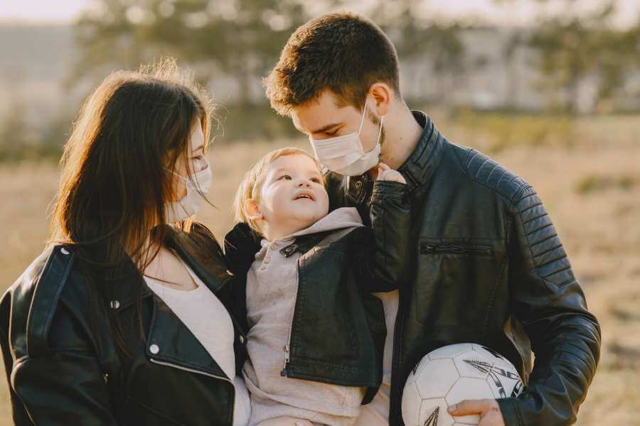 Young parents with toddler wearing masks for COVID-19 protection