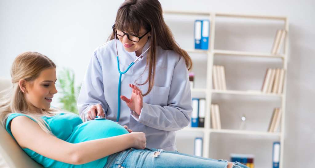 a pregnant woman laying down getting Routine Tests During Pregnancy from female doctor